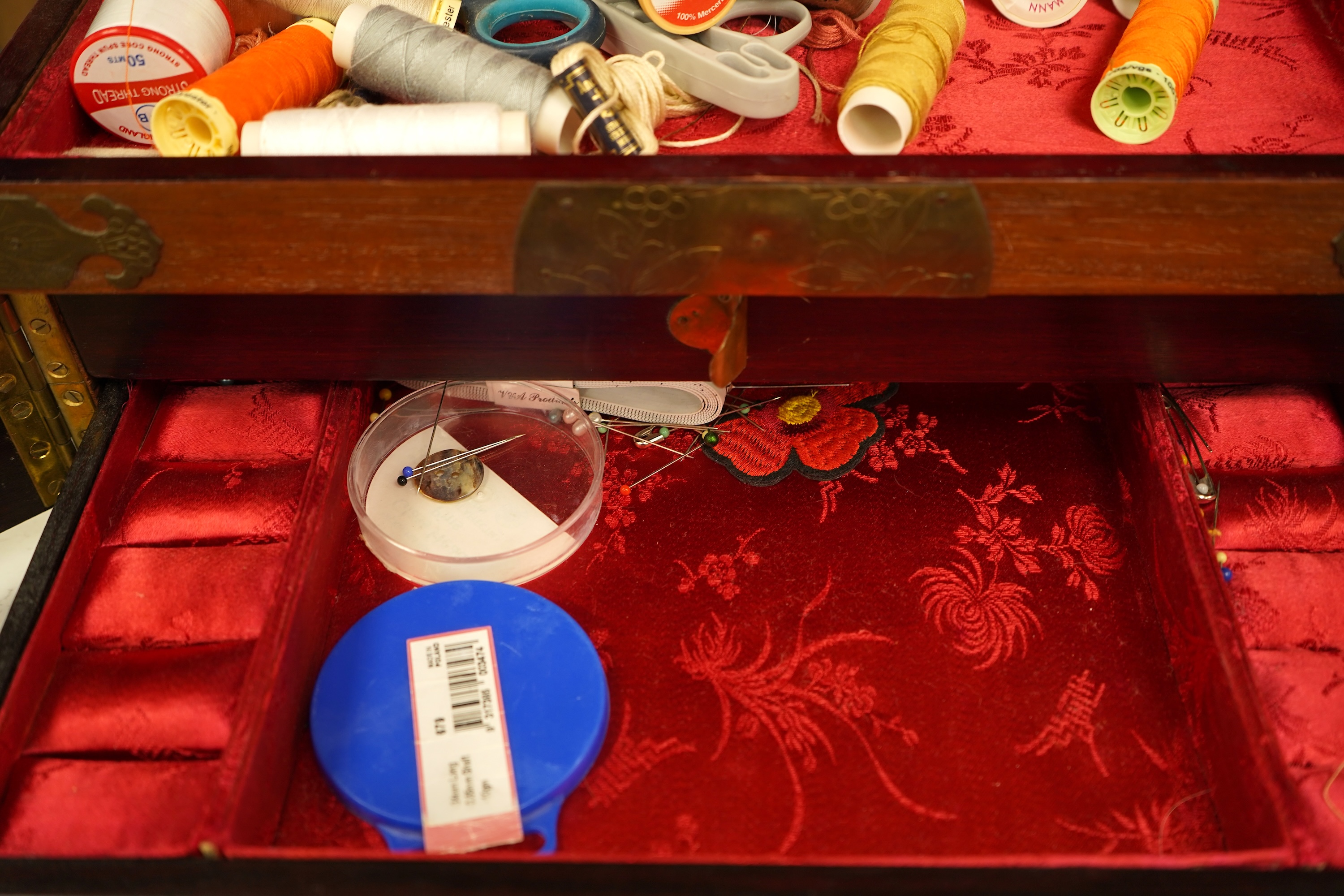 A Chinese brass bound rosewood jewellery box with twin handles, the interior with sewing accessories and threads, 35cm wide